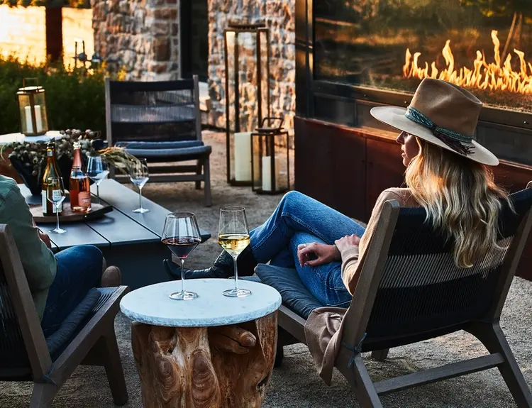 A women with a Cowboy hat sits down next to a cozy fireplace