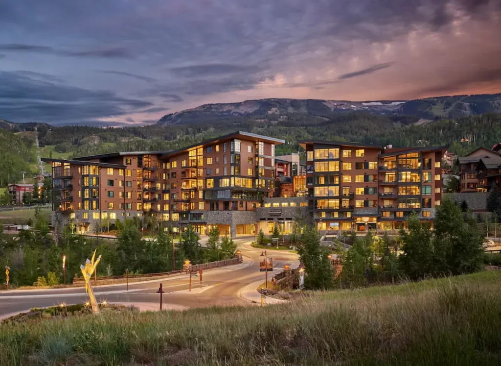 One Snowmass, Snowmass Village, Colorado in the late afternoon, surrounded by vegetation with a mountain in the background
